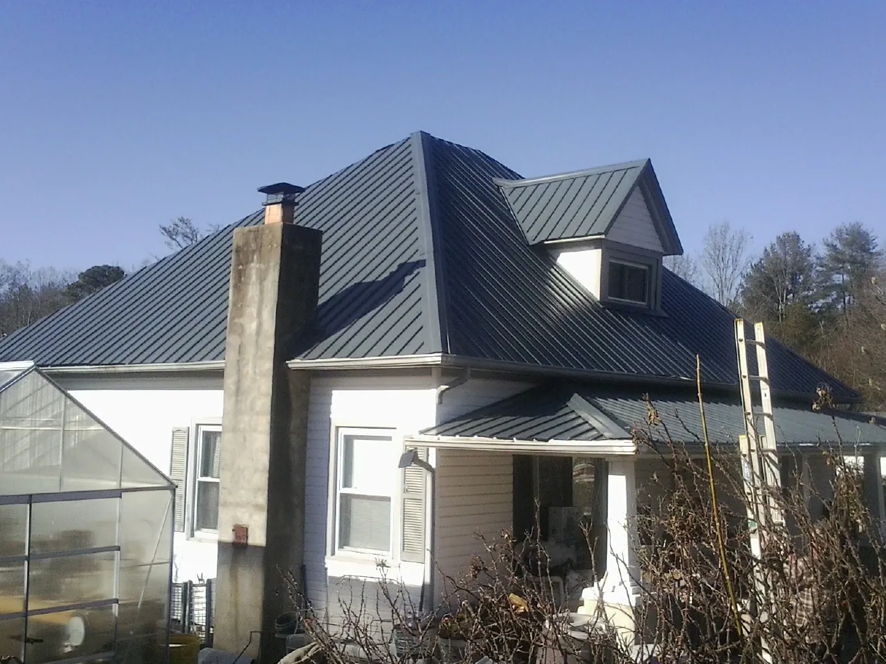 Dark blue standing seam metal roof on a white farmhouse with dormer — Slate & Tile Roof Repair by Roofing Brothers in Los Banos