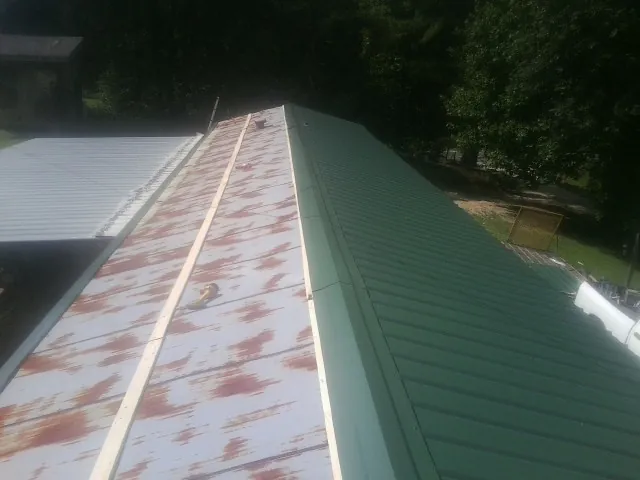 Old rusted panels beside newly installed green metal roofing — Wind Damage Roof Repair by Roofing Brothers in Los Banos