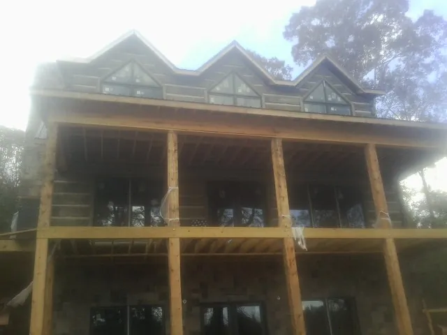 Dormers and porch framing on a large log home under construction — Roof Coating work by our crew in Los Banos