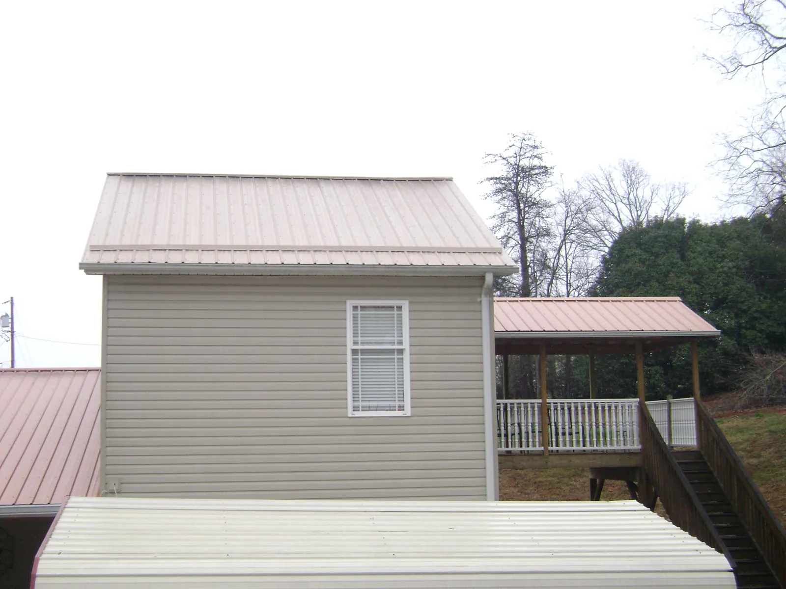 Tan metal roofs on a two story addition and attached porch, from a Roof Replacement job in Los Banos